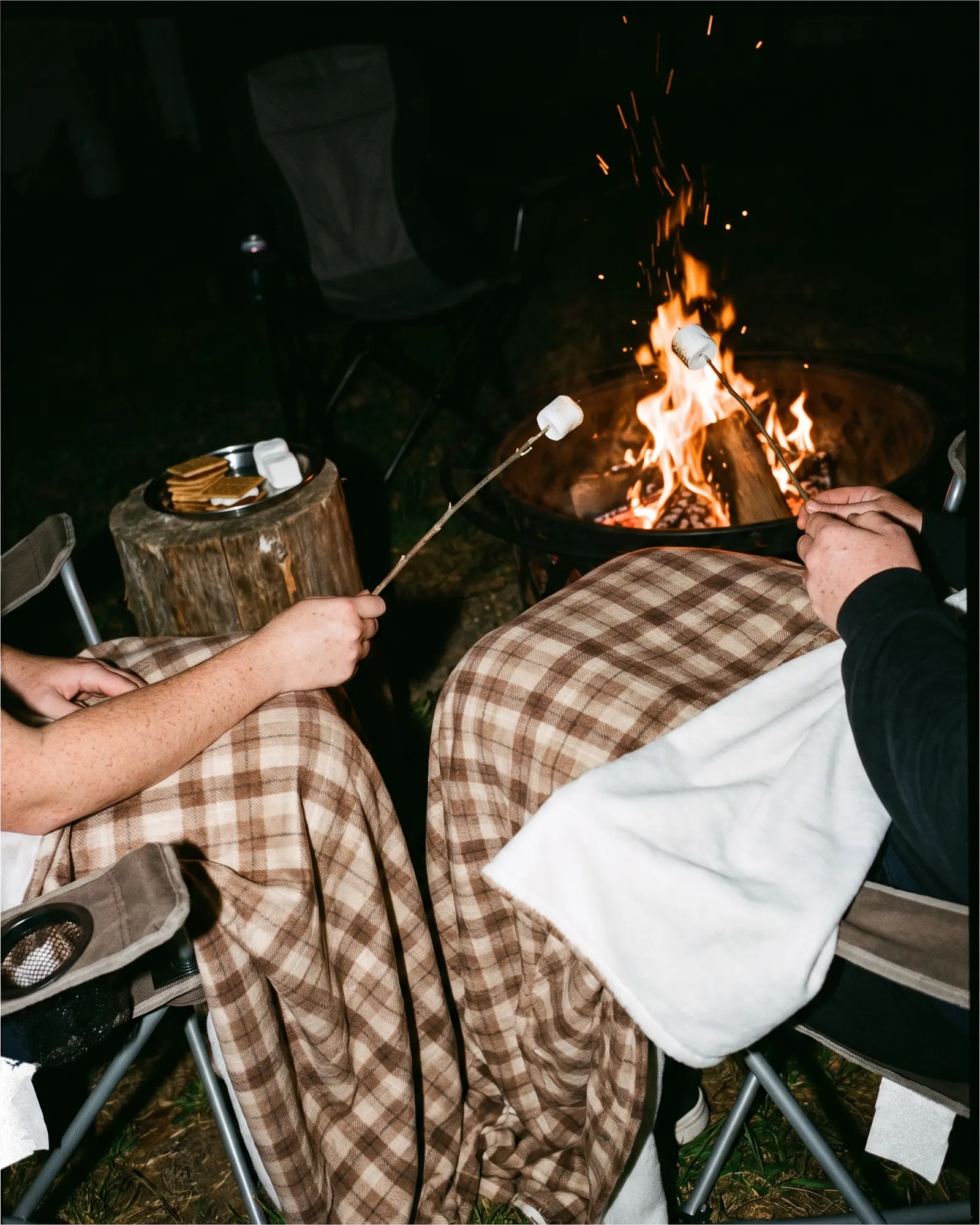 A cabin plaid throw on a wooden chair beside a fire pit.